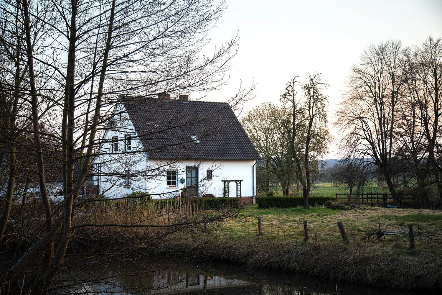 Älteres weißes Einfamilienhaus im ländlichen Umfeld – Entscheidungssituation für Eigentümer, ob sie sanieren oder verkaufen