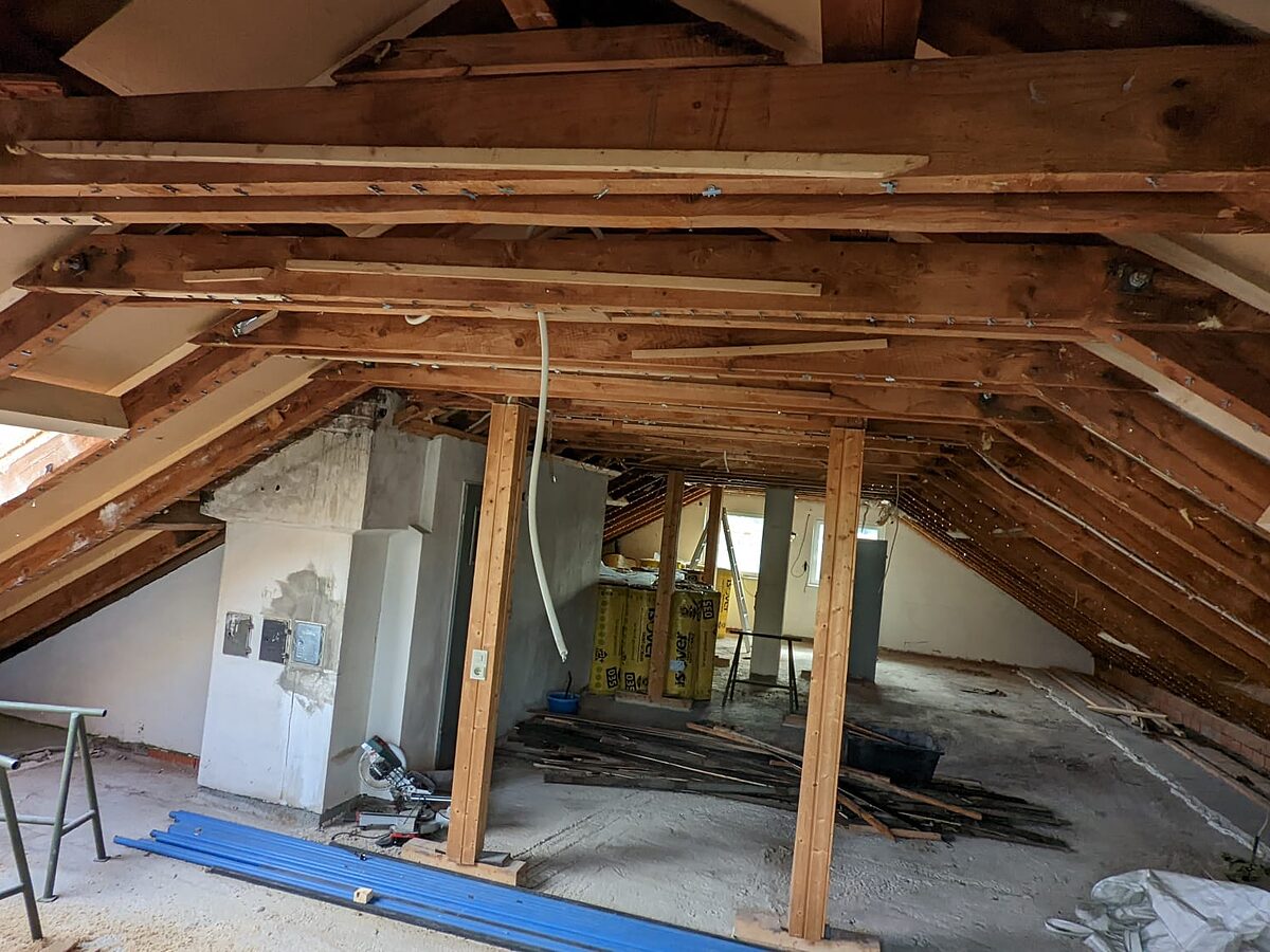 Offener Dachstuhl mit tragenden Holzstützen vor dem Dachgeschossausbau