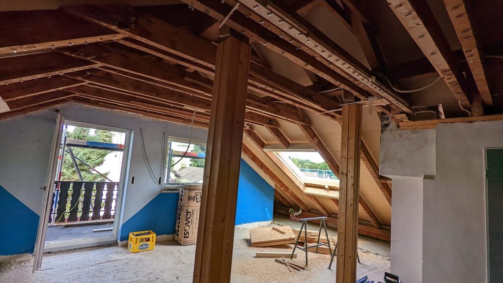 Dachboden zu Beginn des Ausbaus, mit Holzstützen und offenem Dachstuhl