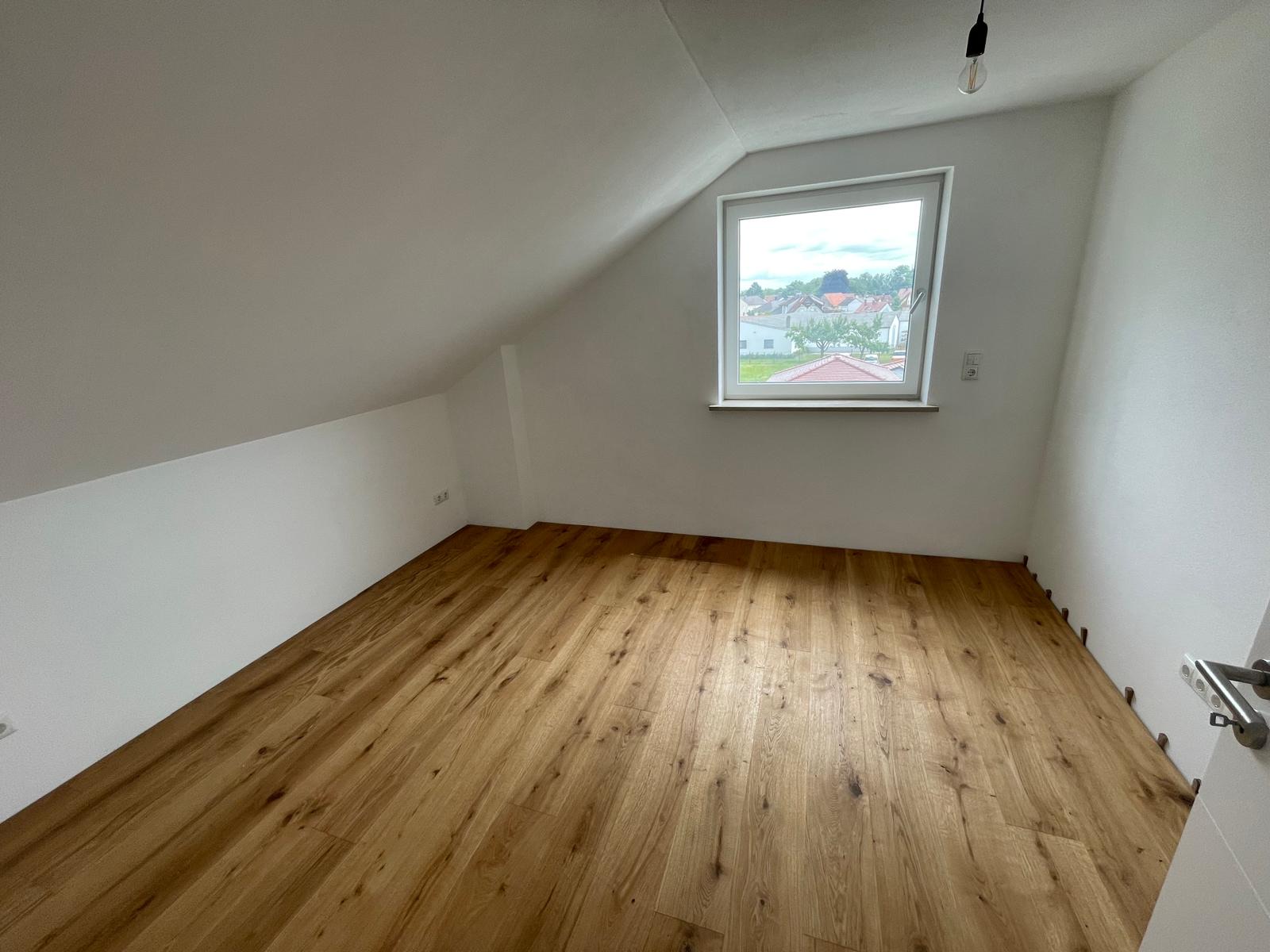 Schlafzimmer mit Giebelfenster und Eichenparkett in der ausgebauten Dachgeschosswohnung