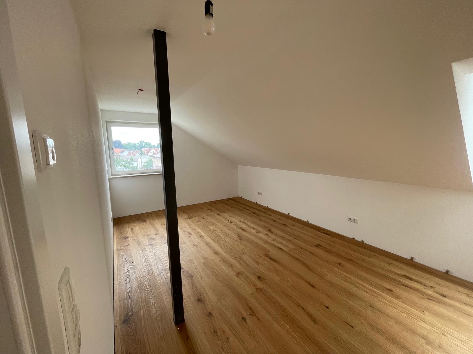 Zimmer mit tragender Stahlstütze und Fenster in der ausgebauten Dachgeschosswohnung